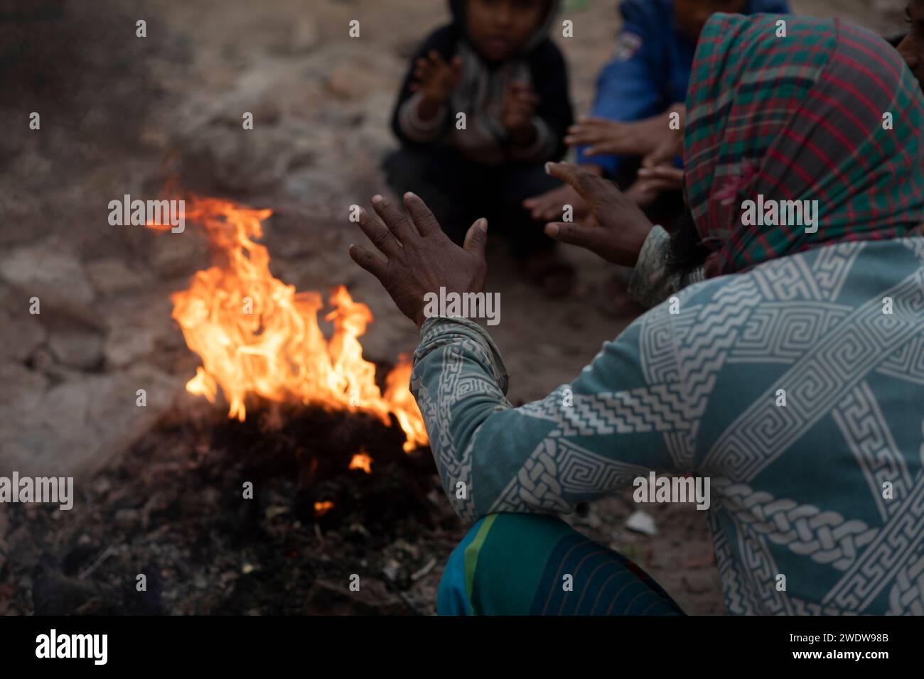 Dhaka, Bangladesh. 22nd Jan, 2024. People warm themselves around a bon
