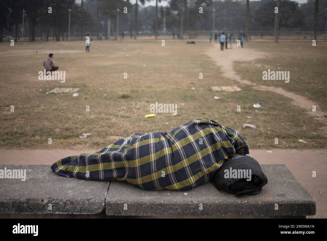 Dhaka, Bangladesh. 22nd Jan, 2024. A street man covers himself with a