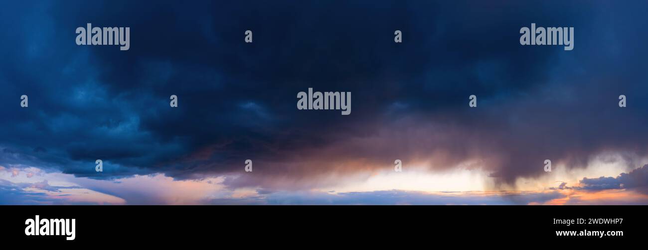 Dramatic sky with dark rainy clouds at sunset. Nature background. Stock Photo