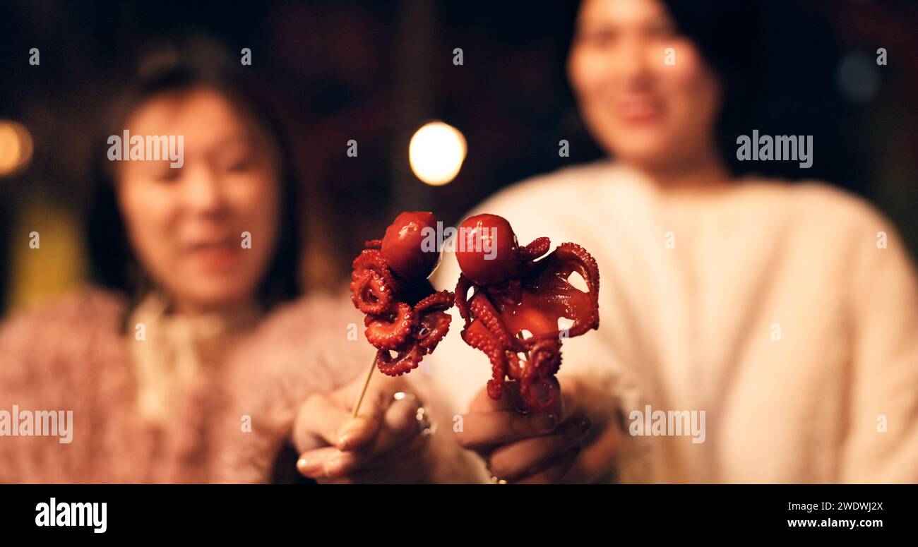 Women, Japan and travel street food at night for octopus delicacy, culture or traditional. Female people, snack and stick for tourism eating Stock Photo