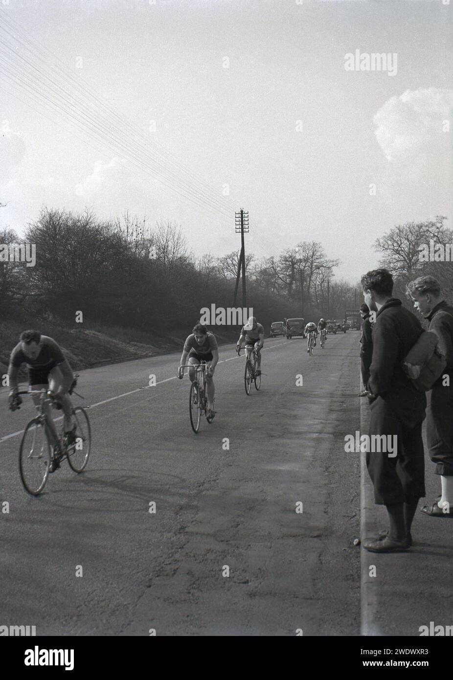 1952, historical, cycle sport, road race, competitors riding in the Daily Express Tour of Britain, England, UK, watched by spectators at the roadside, in plus fours, common atire for men in this and previous eras. Stock Photo