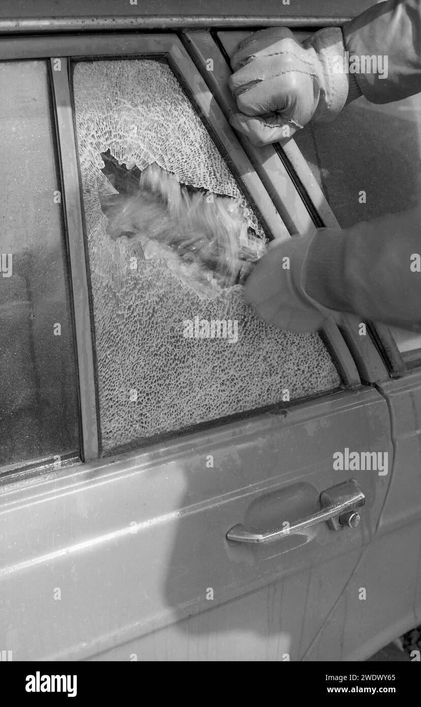 1970s, historical, a gloved hand thief breaking a car window, a back