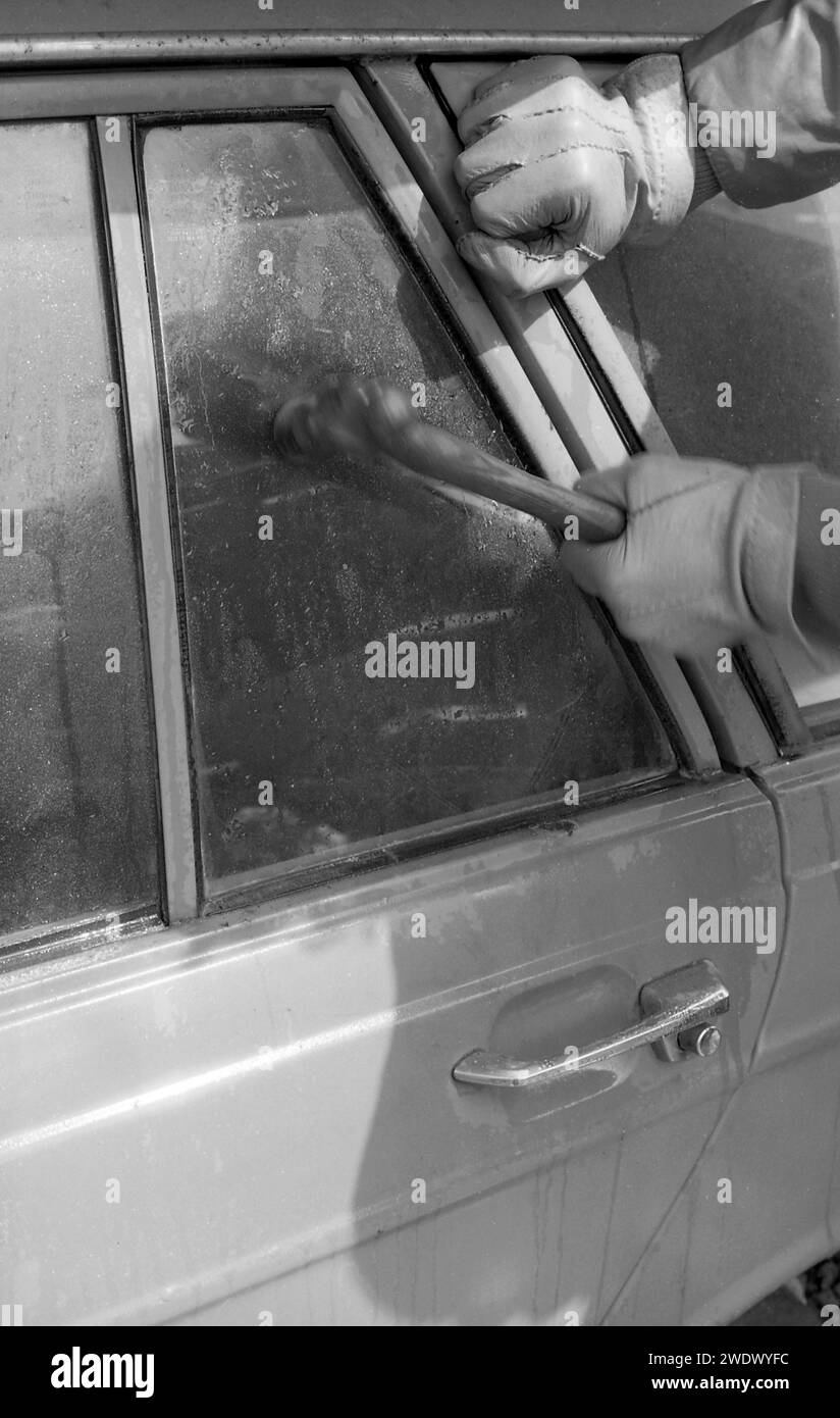 1970s, historical, gloved hands of a car thief breaking a car window, a