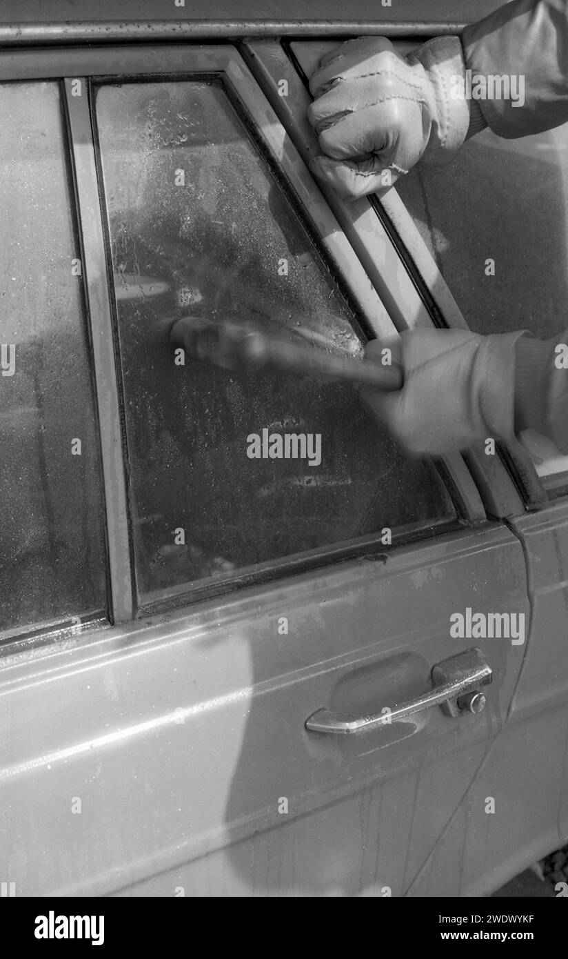 1970s, historical, a thief breaking a car window, a back vent window of