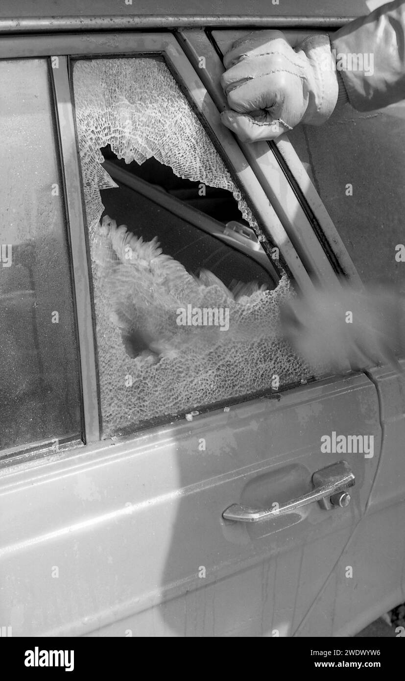 1970s, historical, a thief breaking a car window, a back vent window of