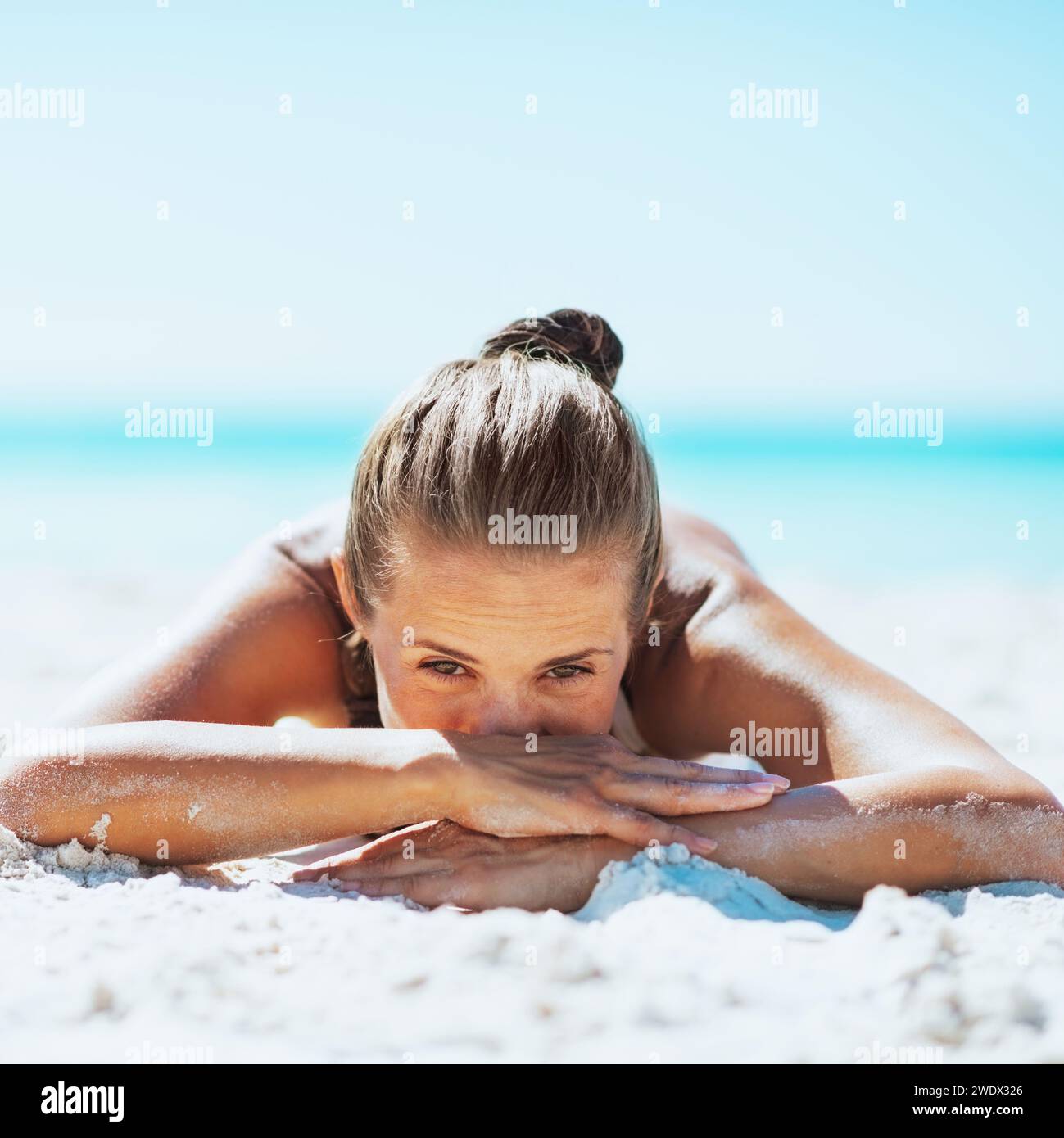 Young woman in swimsuit laying on sandy beach Stock Photo - Alamy
