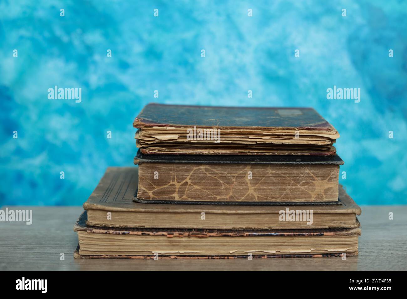 Stack of old books on a wooden table with blue wall background Stock ...