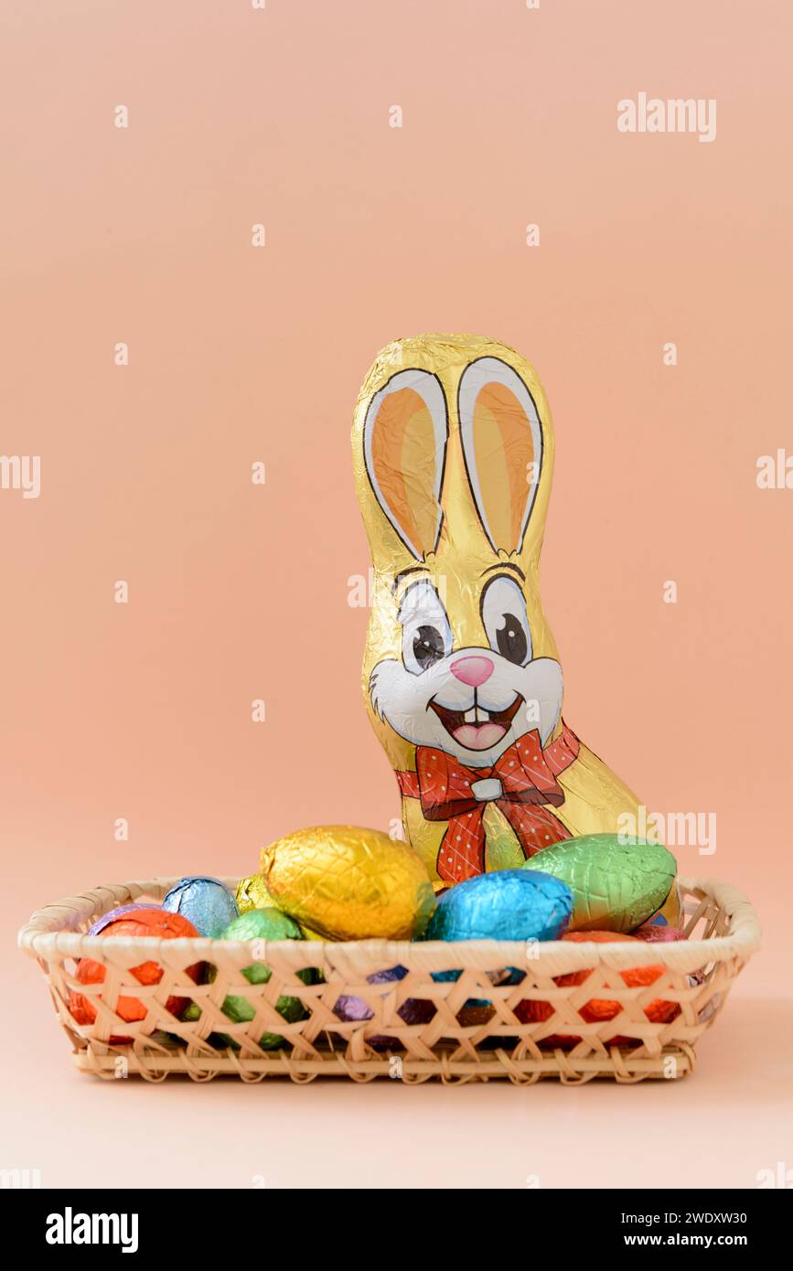 Still life with chocolate Easter eggs and a chocolate bunny on a background of a soft orange tone. Stock Photo