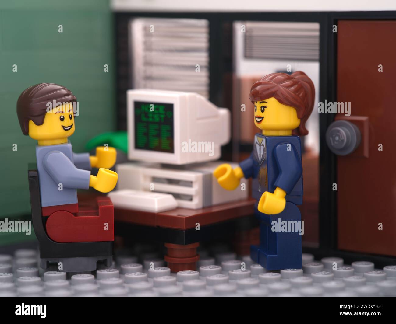 Tambov, Russian Federation - January 21, 2024 A Lego businessperson minifigure sitting behind a computer and talking with another lego businessperson Stock Photo