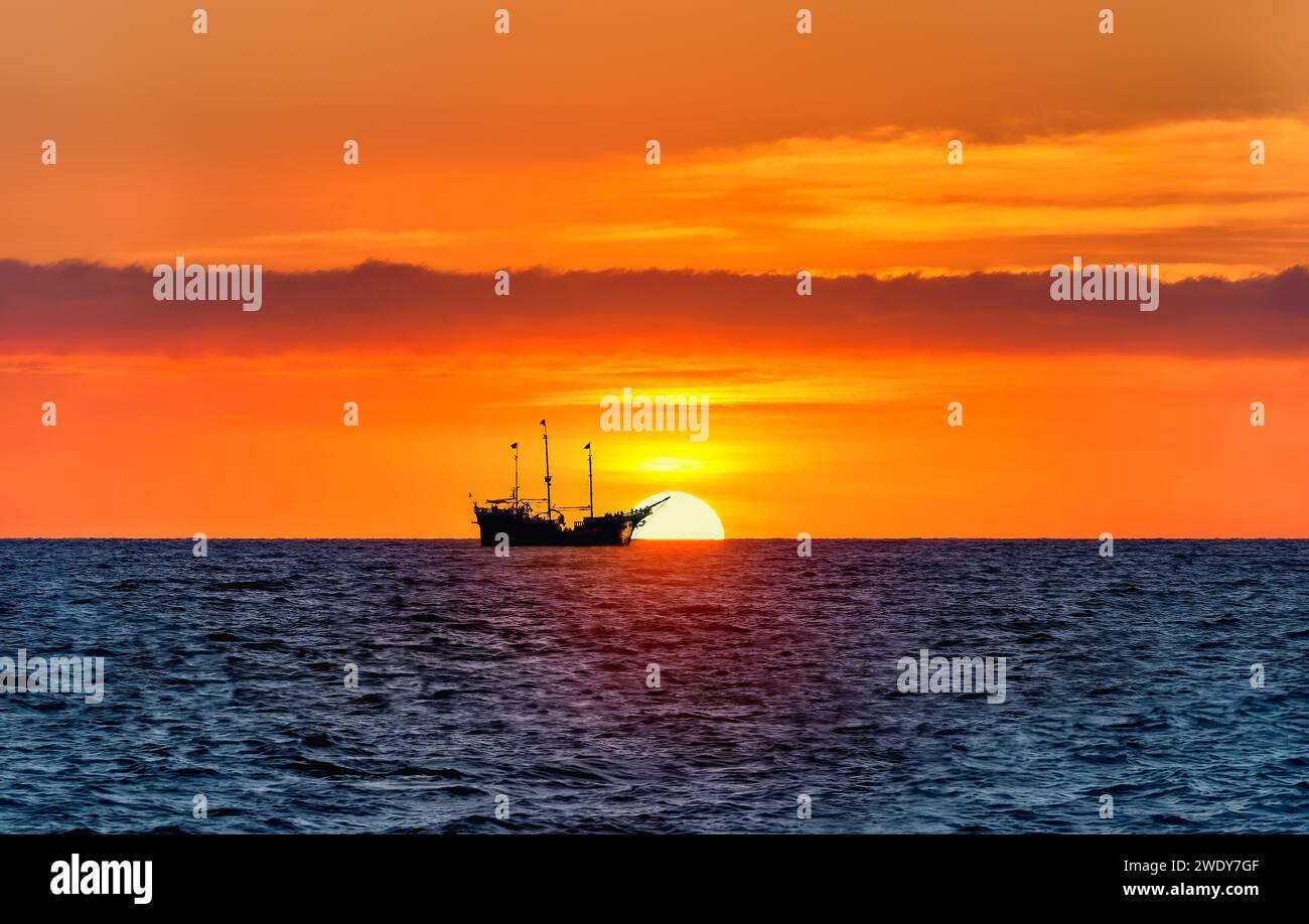A Silhouette Of A Pirate Ship At Sea With A Colorful Sunset On the ...