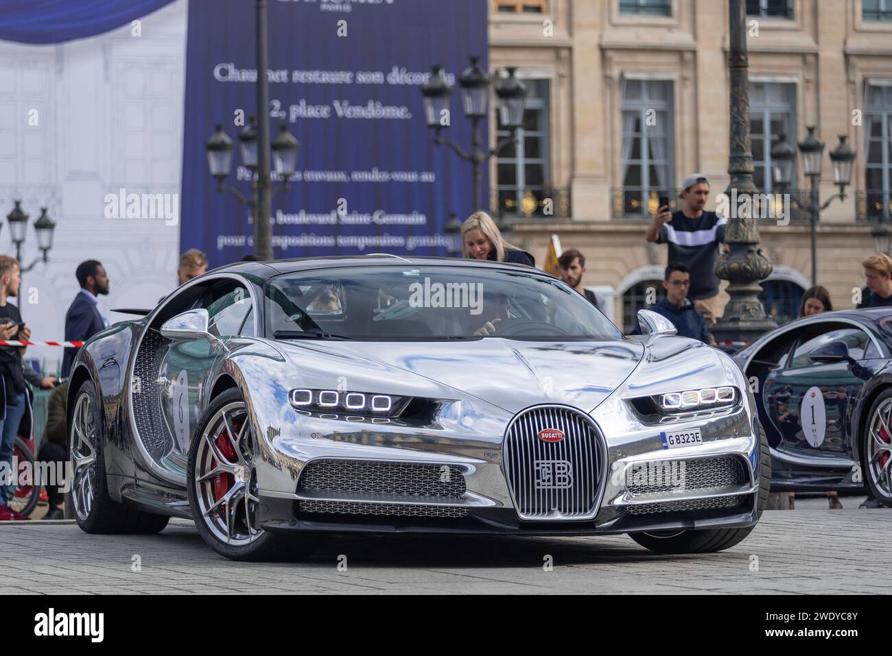 Paris, France - Nocturne and Argent Metallic Bugatti Chiron La Mer Argentée driving in the Place Vendôme. Stock Photo