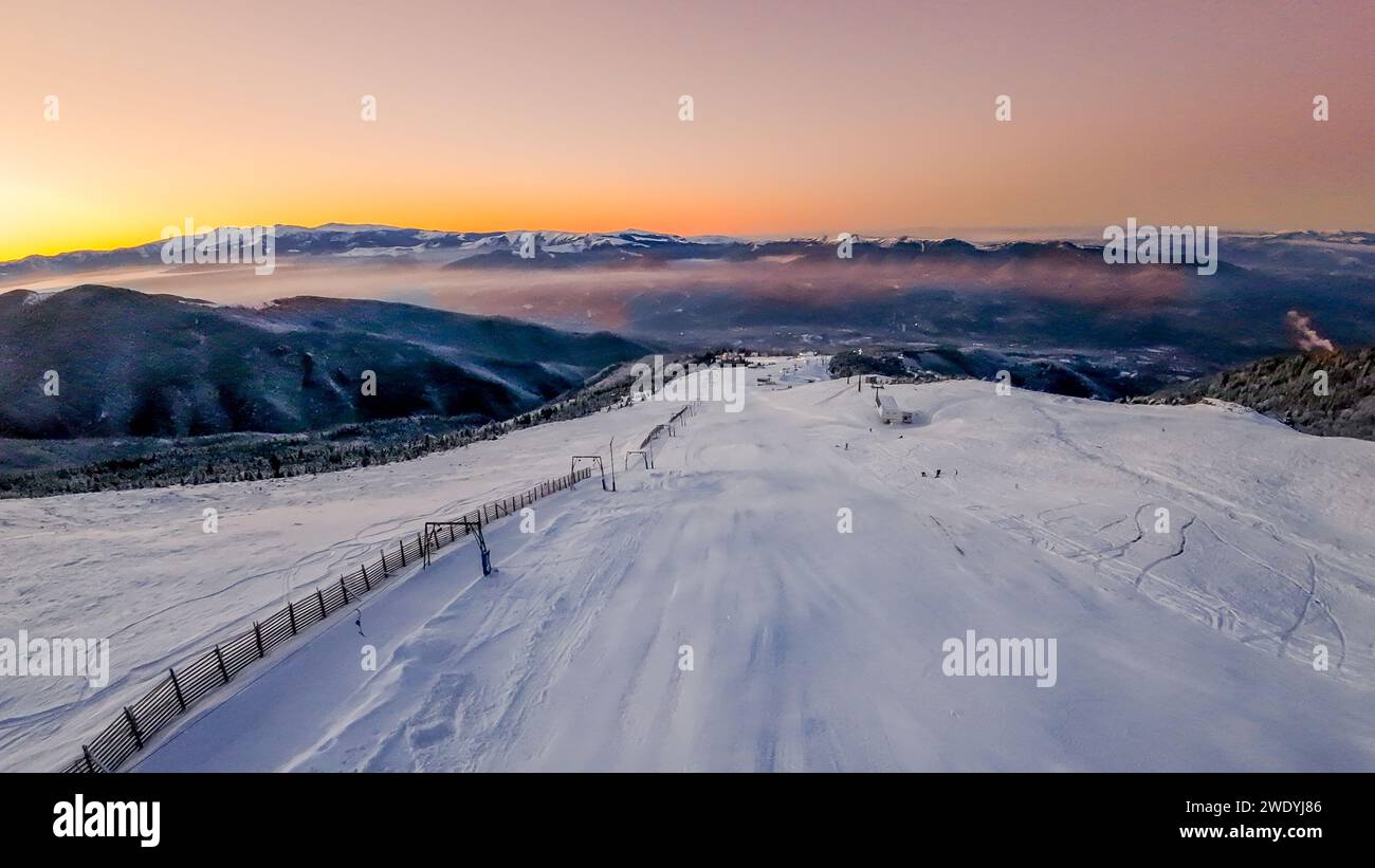 Ski slope in snow-covered valley at sunset Stock Photo