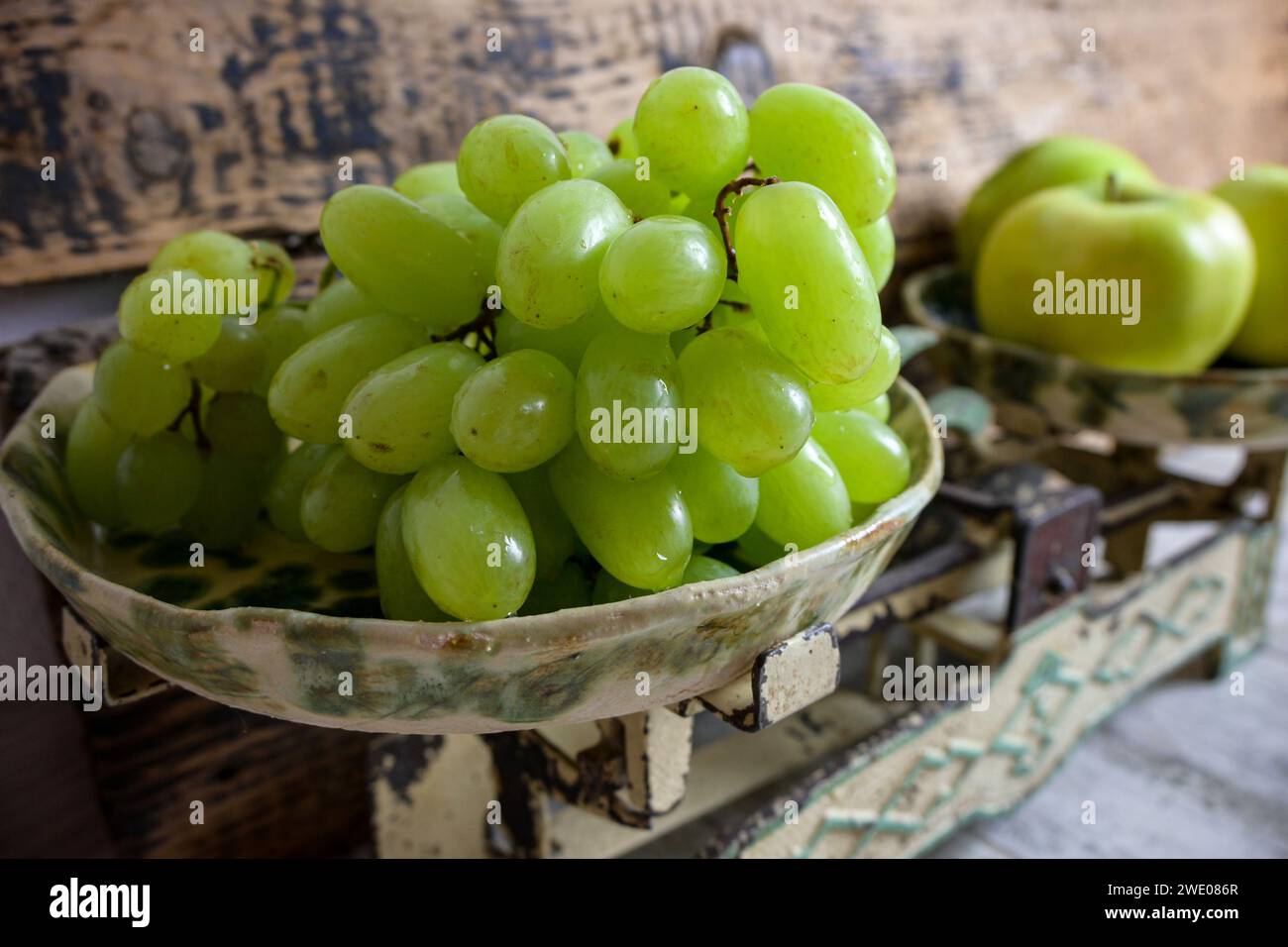 green grapes and apples on a retro scale, wooden background. Stock Photo