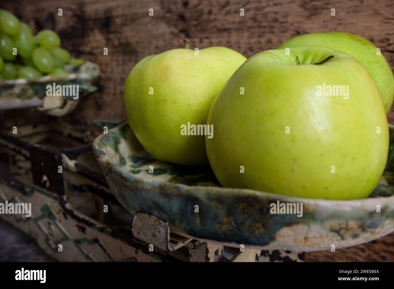 green grapes and apples on a retro scale, wooden background. Stock Photo