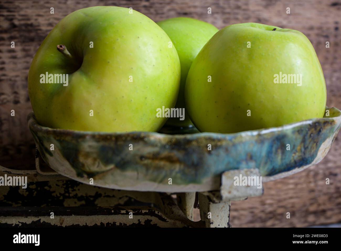 green and red apples on a scale and wooden background, retro style - side view. Stock Photo