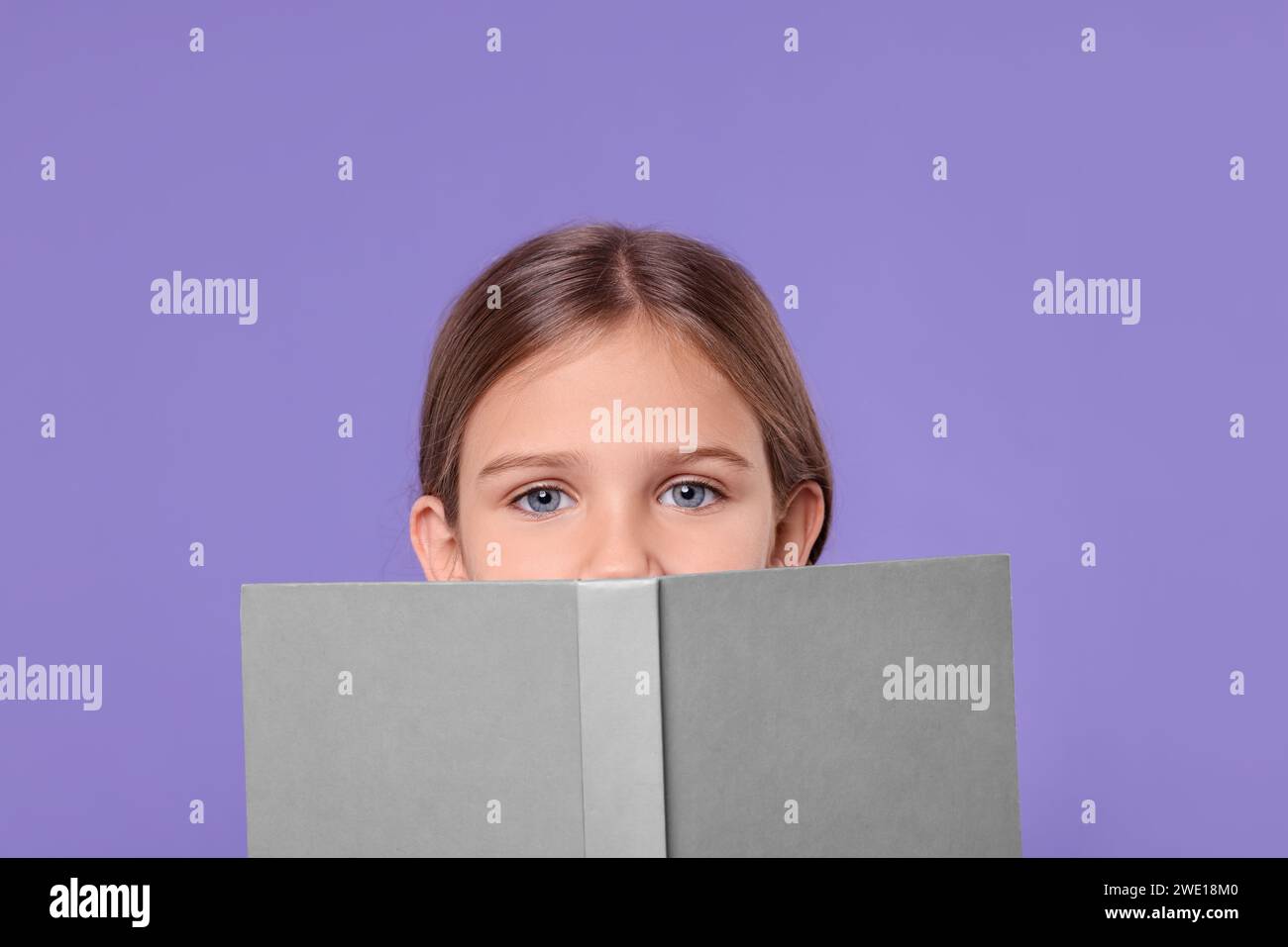 Cute schoolgirl with open book on violet background Stock Photo - Alamy