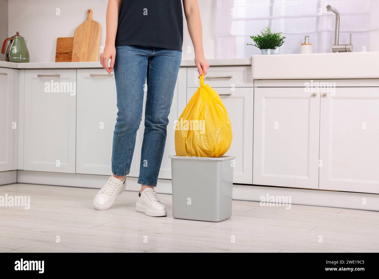 Woman taking garbage bag out of trash bin in kitchen, closeup Stock Photo