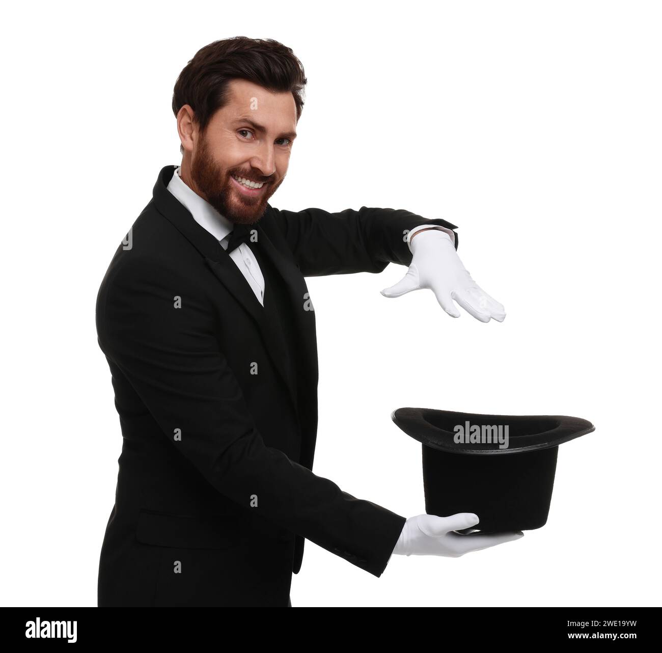 Happy magician showing magic trick with top hat on white background ...