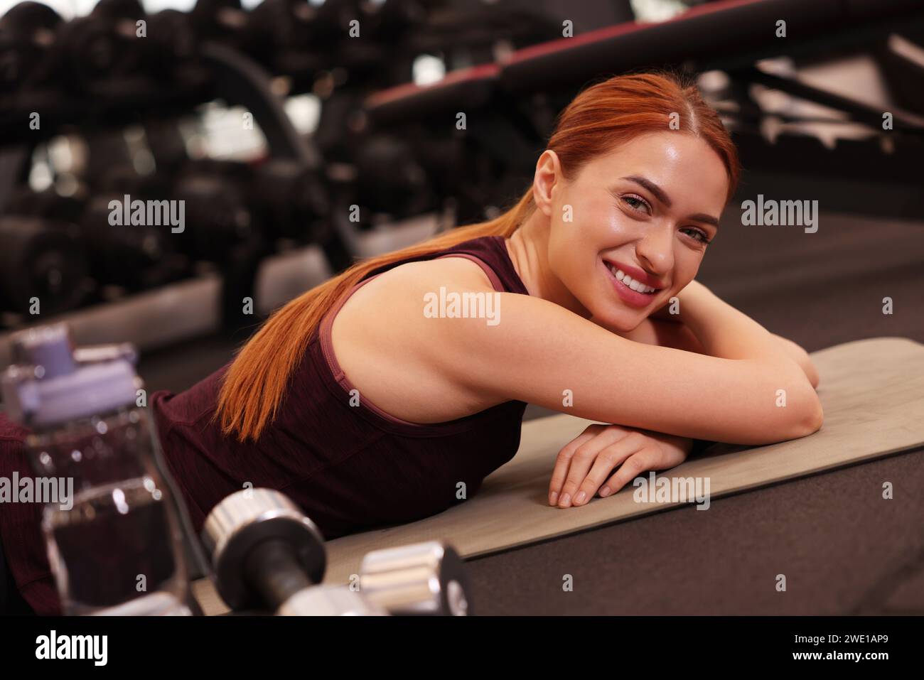 Happy young woman lying on mat in gym Stock Photo - Alamy