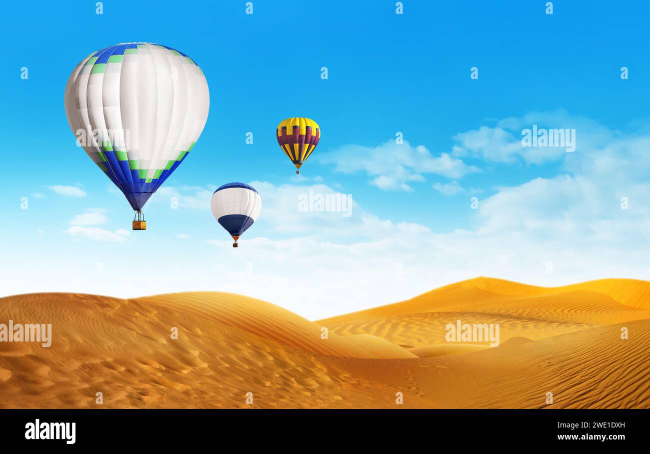 Bright hot air balloons flying in blue sky over sandy desert Stock Photo
