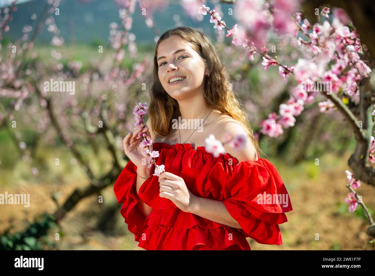 Portrait of happy girl in red dress in blooming spring garden Stock Photo