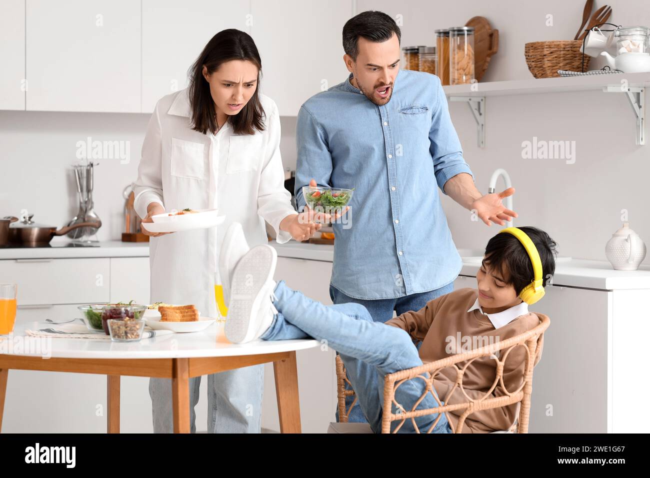 Teenage boy with his feet on table and angry parents during dinner in