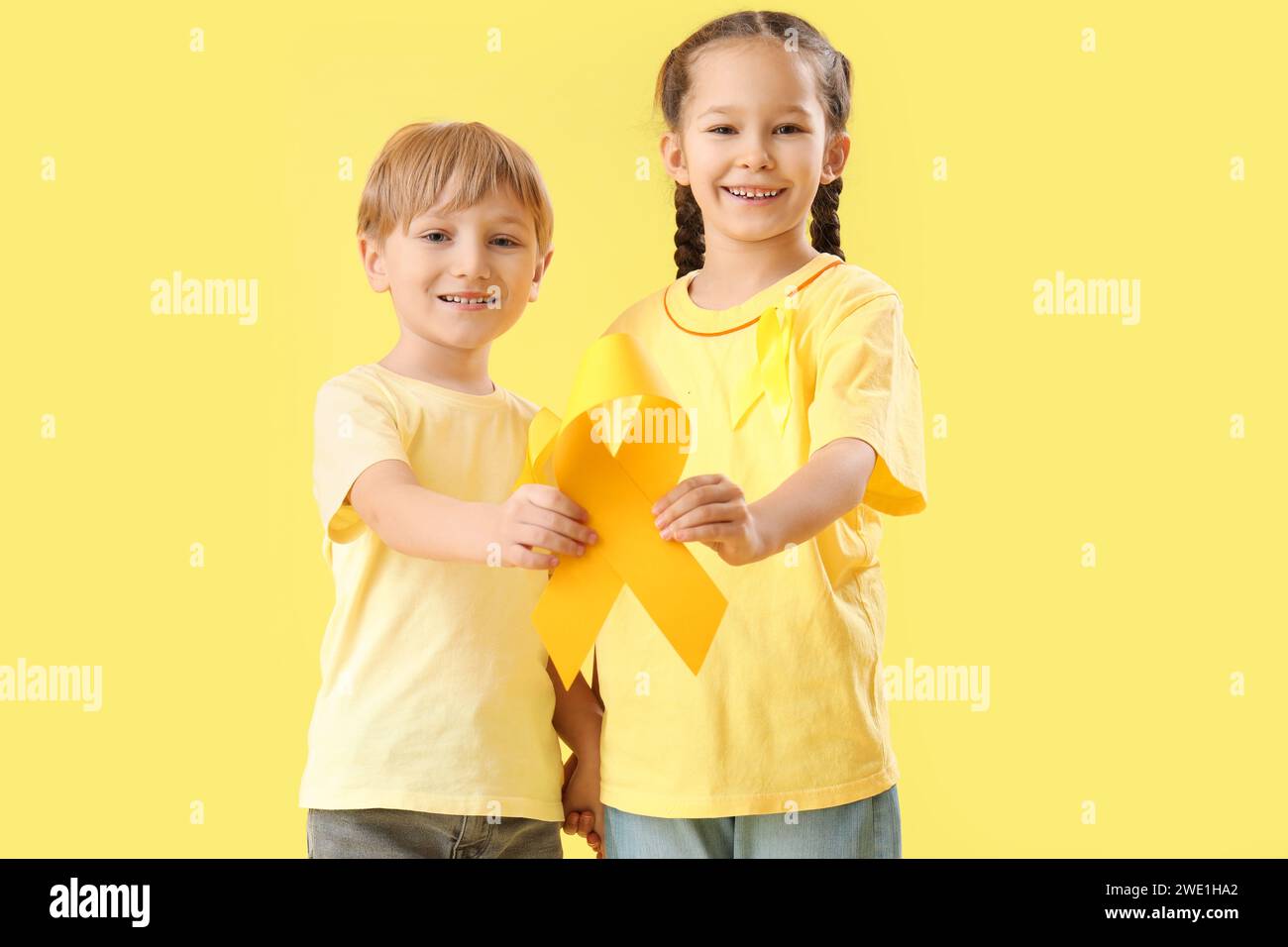 Cute little children with yellow ribbons on color background. Childhood ...