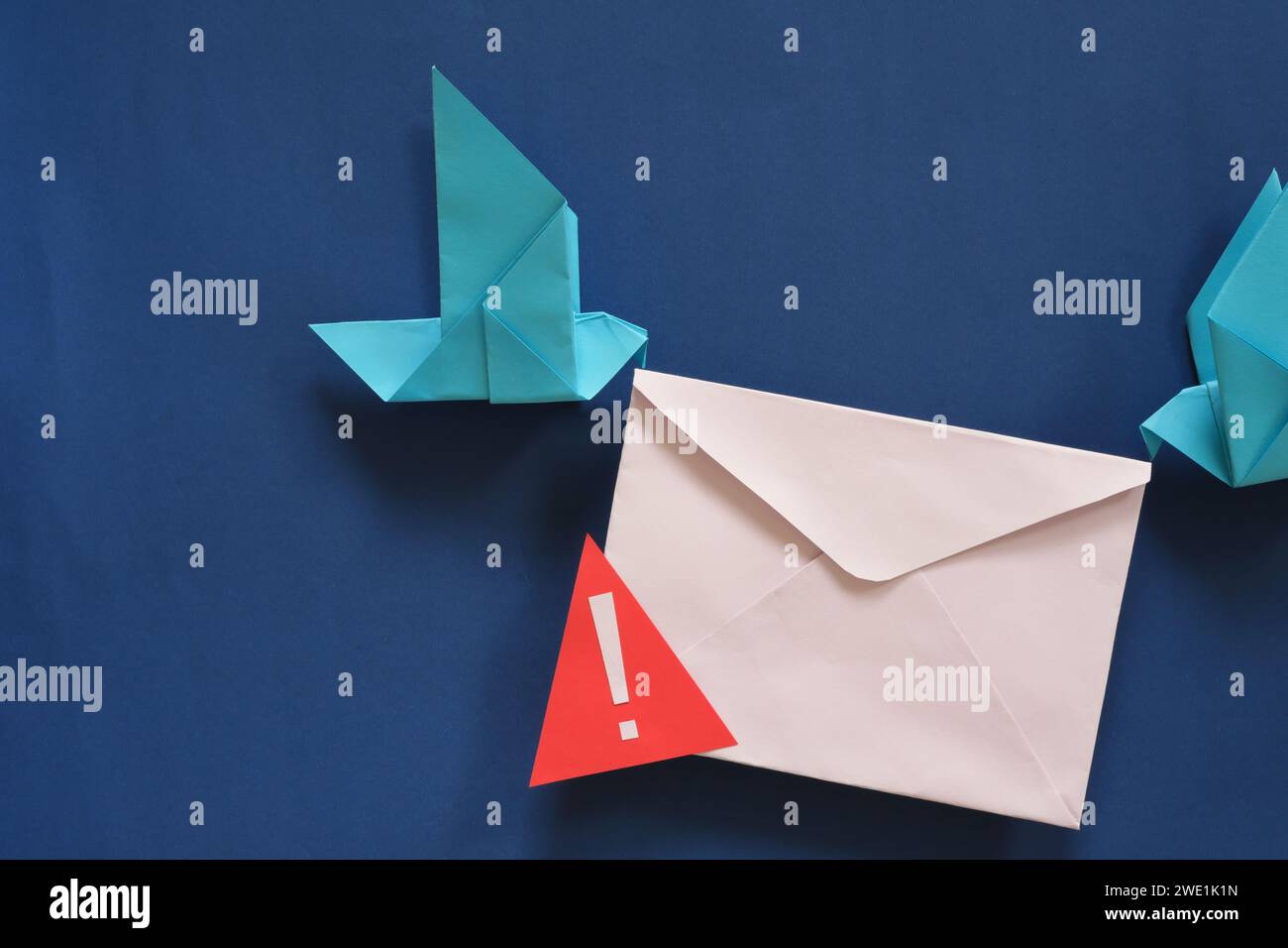 Two birds paper origami carrying letter envelope with warning sign. Phishing email scam and fraudulent message. Stock Photo