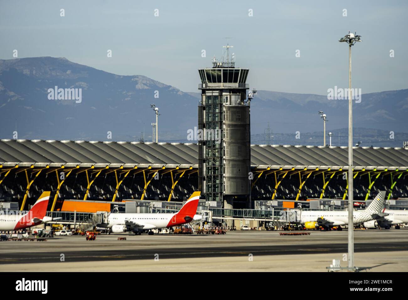 Airport control tower next to a terminal with fingers extended towards the planes Stock Photo