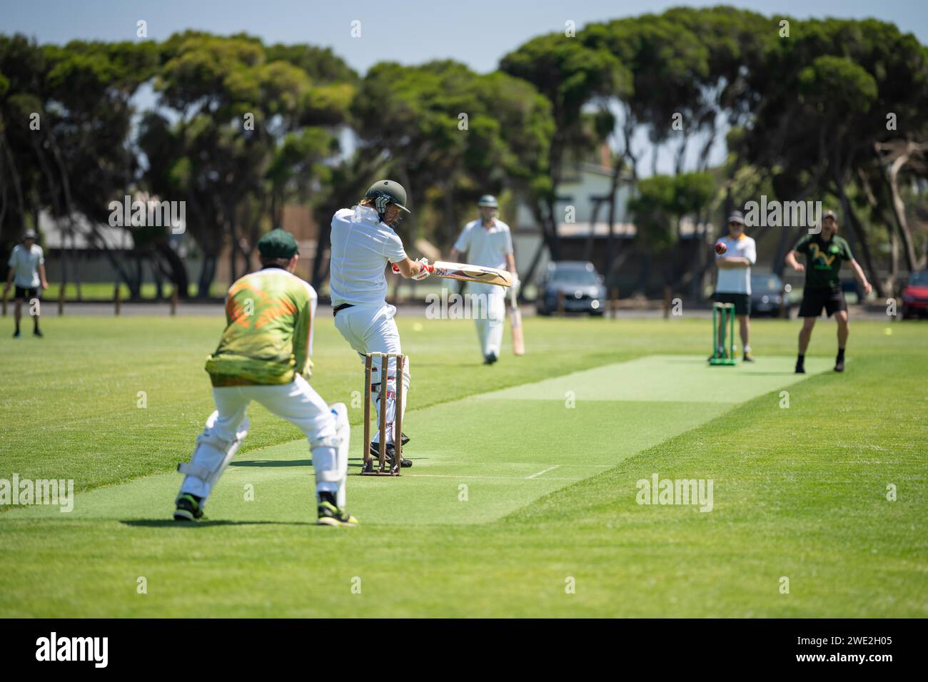 a local cricket match being played on a green cricket oval in summer in australia. australian