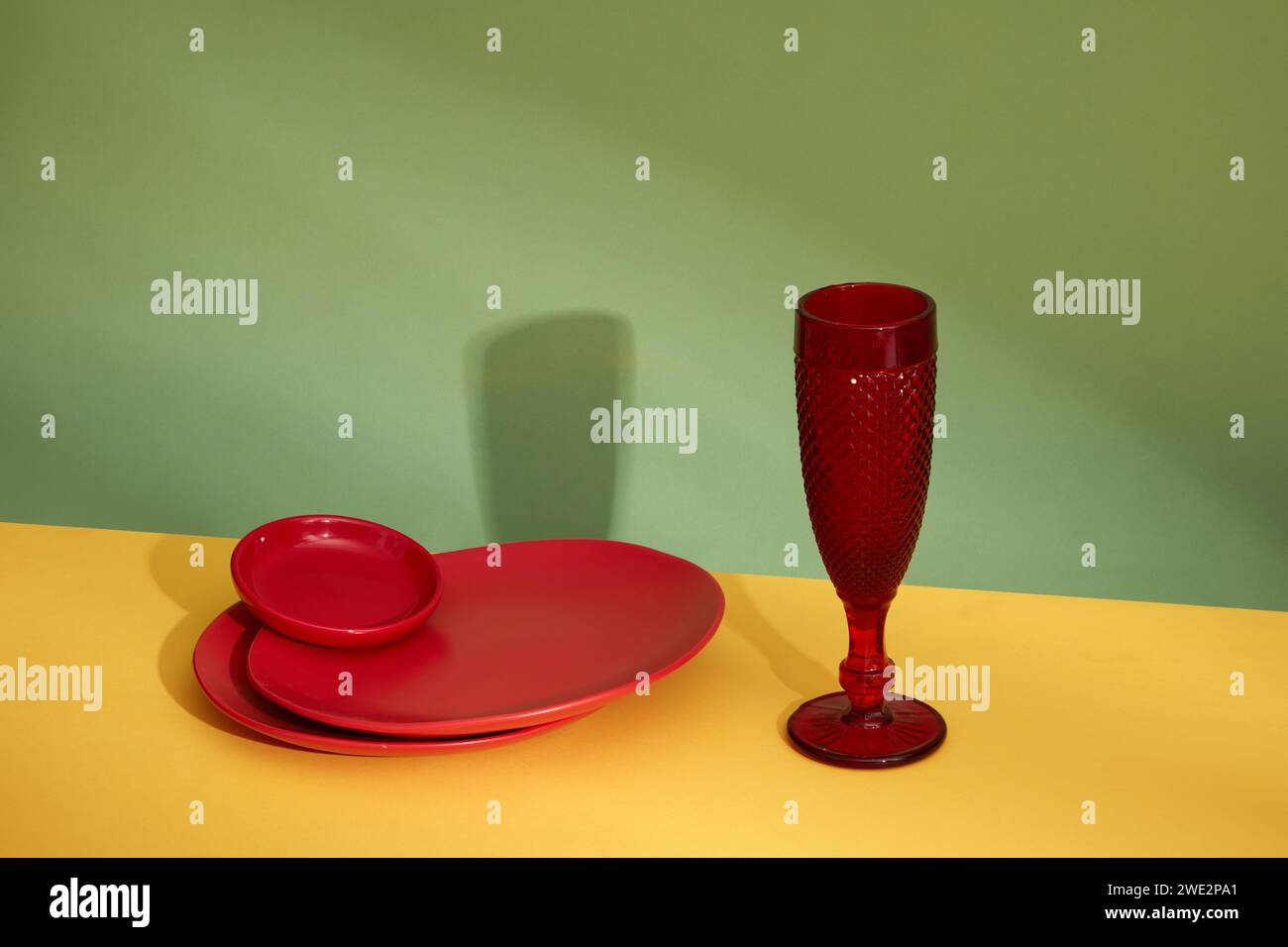 Front view of stacked of round red plates and red glass cup decorated