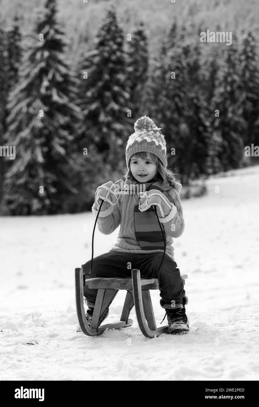 Child boy sledding in winter. Kid riding on snow slides in winter. Wonderful Christmas scene. Stock Photo
