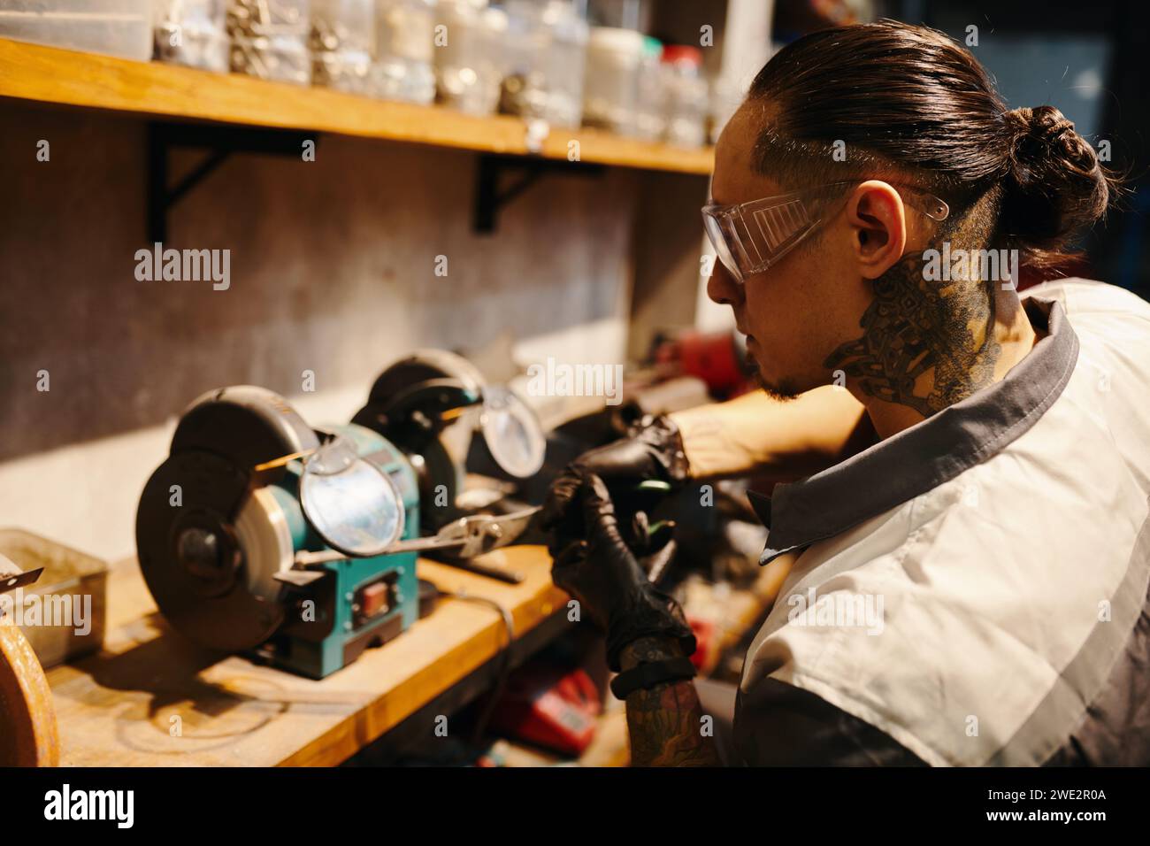 Mechanic in protective googles working at workbench in his garage Stock Photo