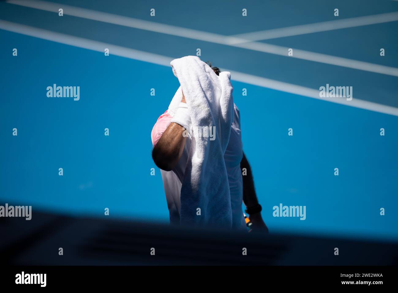 tennis player drying off with a towel on a tennis court in summer in