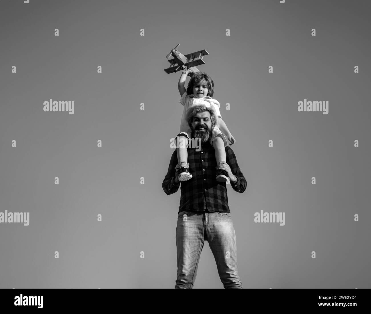 Father carrying his son on shoulders. Father and son playing with toy