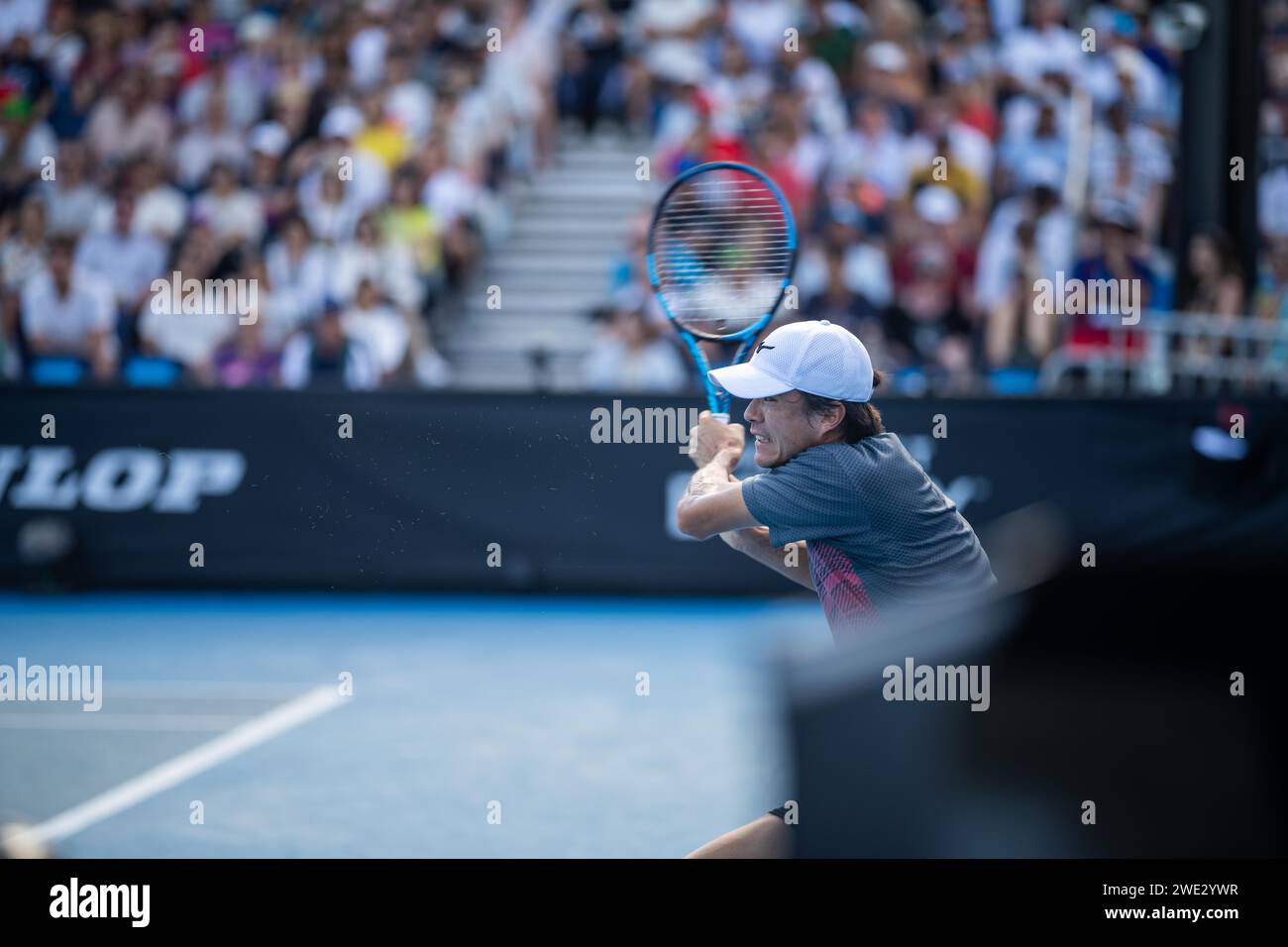 Amateur playing tennis at a tournament. professinal tennis player serving in front of a packed tennis crowd of tennis spectators watching the tennis i Stock Photo