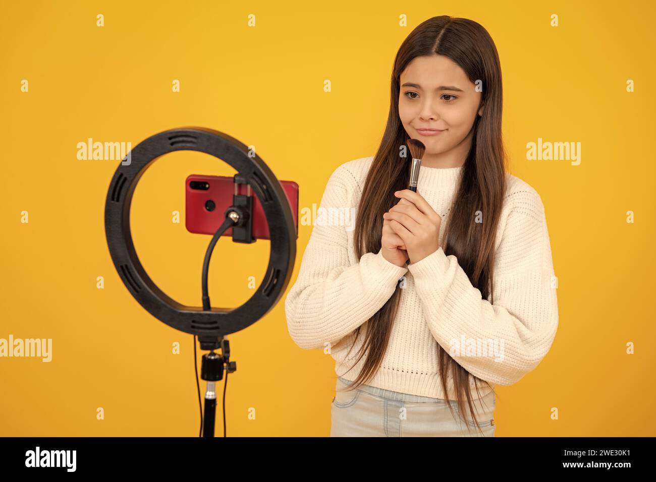 Beauty blog. Teen girl blogger influencer use selfie led lamp and smartphone on tripod for making online video tutorial. Teenager vlogger making vlog Stock Photo