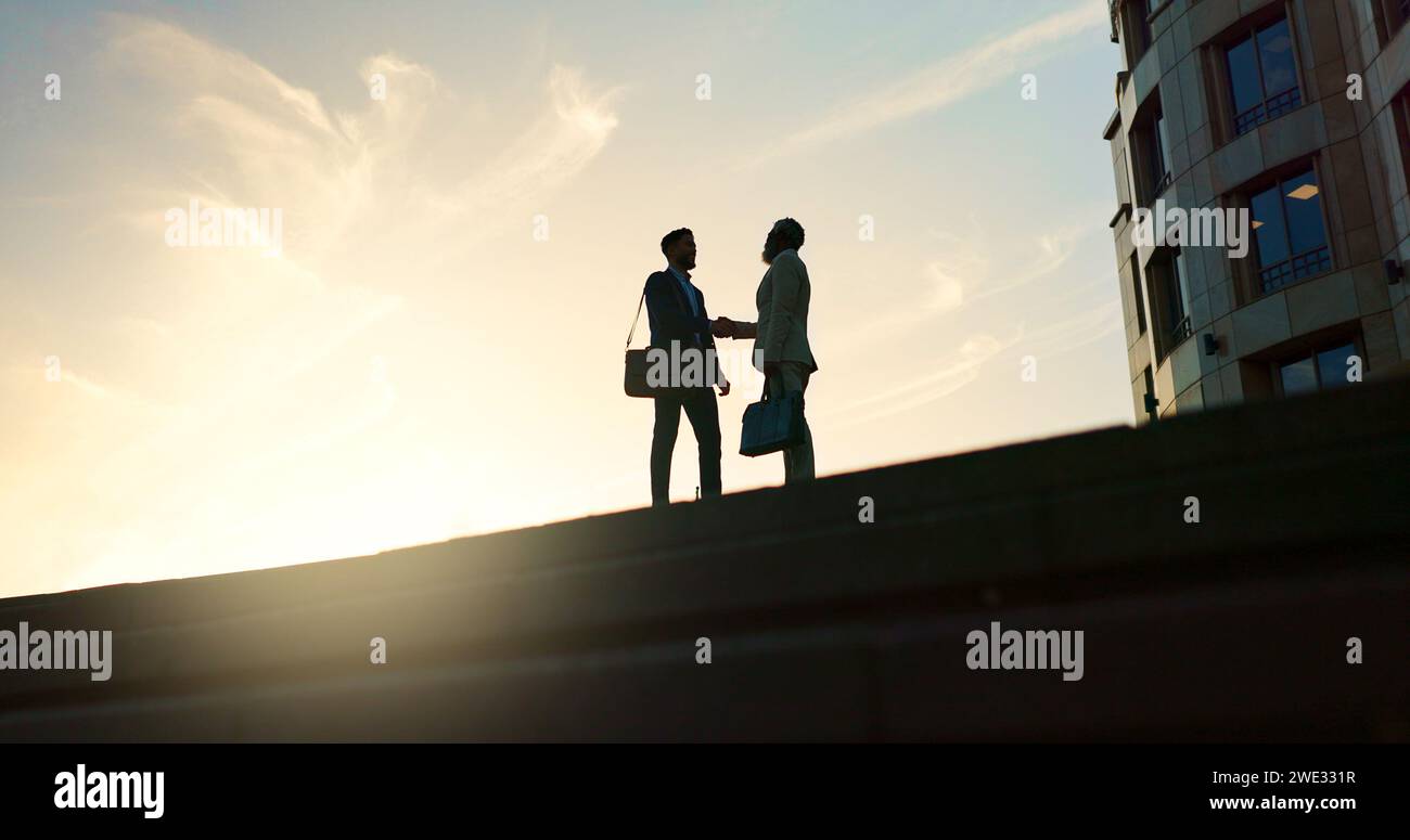 Business people, handshake and city silhouette for partnership, outdoor introduction and travel meeting. Corporate clients or men shaking hands for Stock Photo