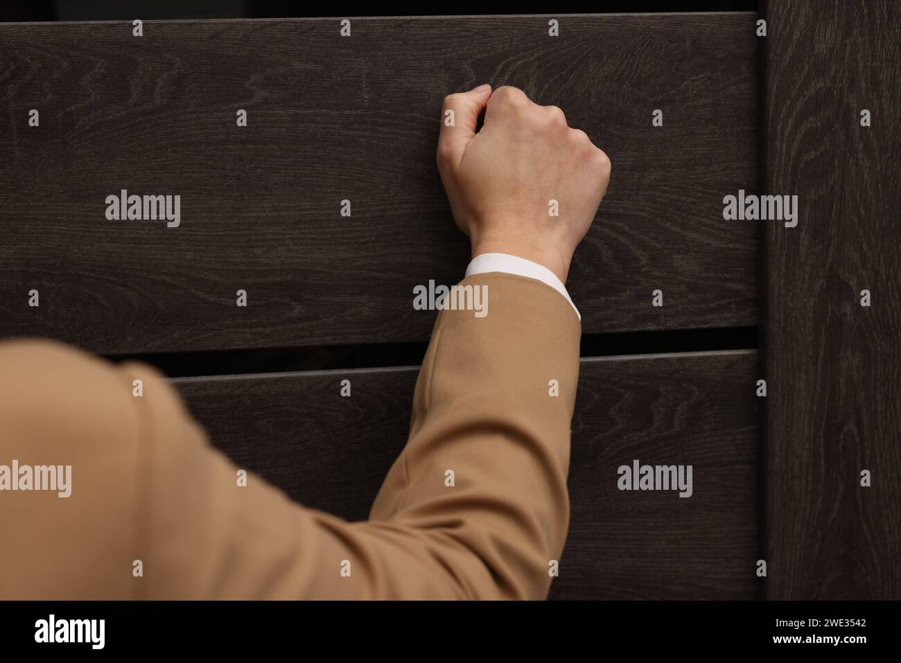 Collector knocking on door indoors, closeup view Stock Photo