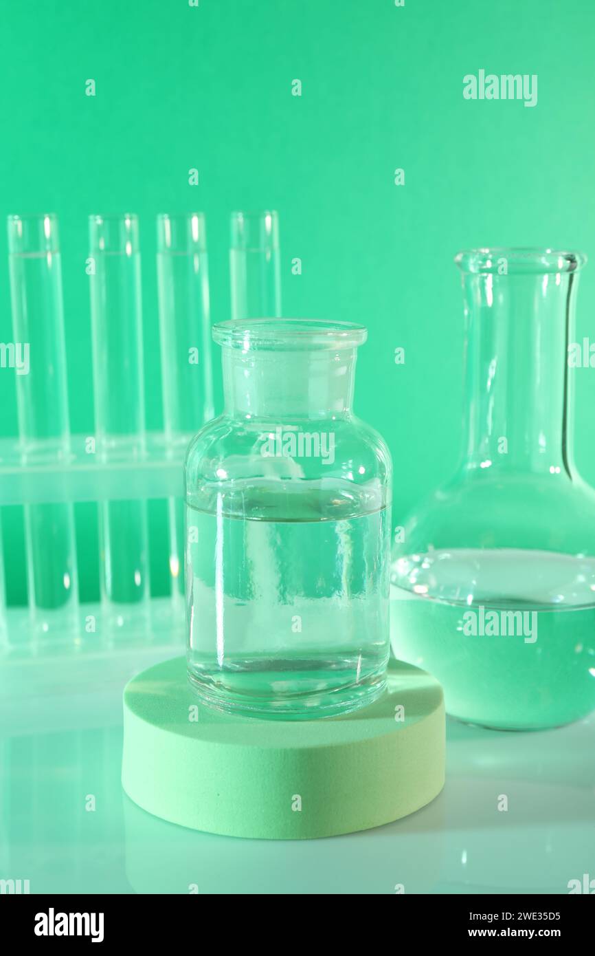 Laboratory analysis. Glass flasks and test tubes on table against green ...