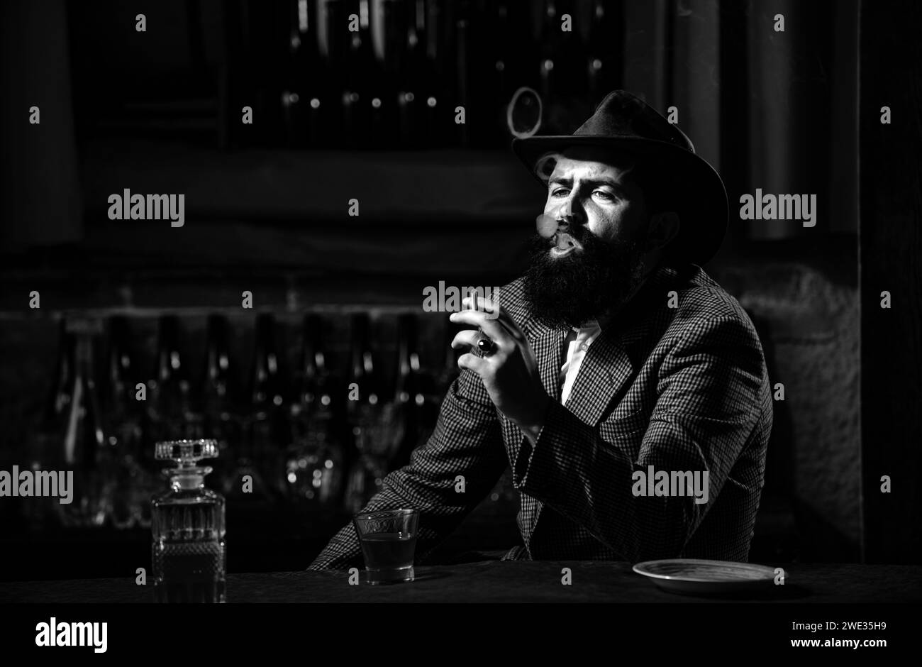 Attractive man smoking cigarettes with glass of wiskey. Stock Photo