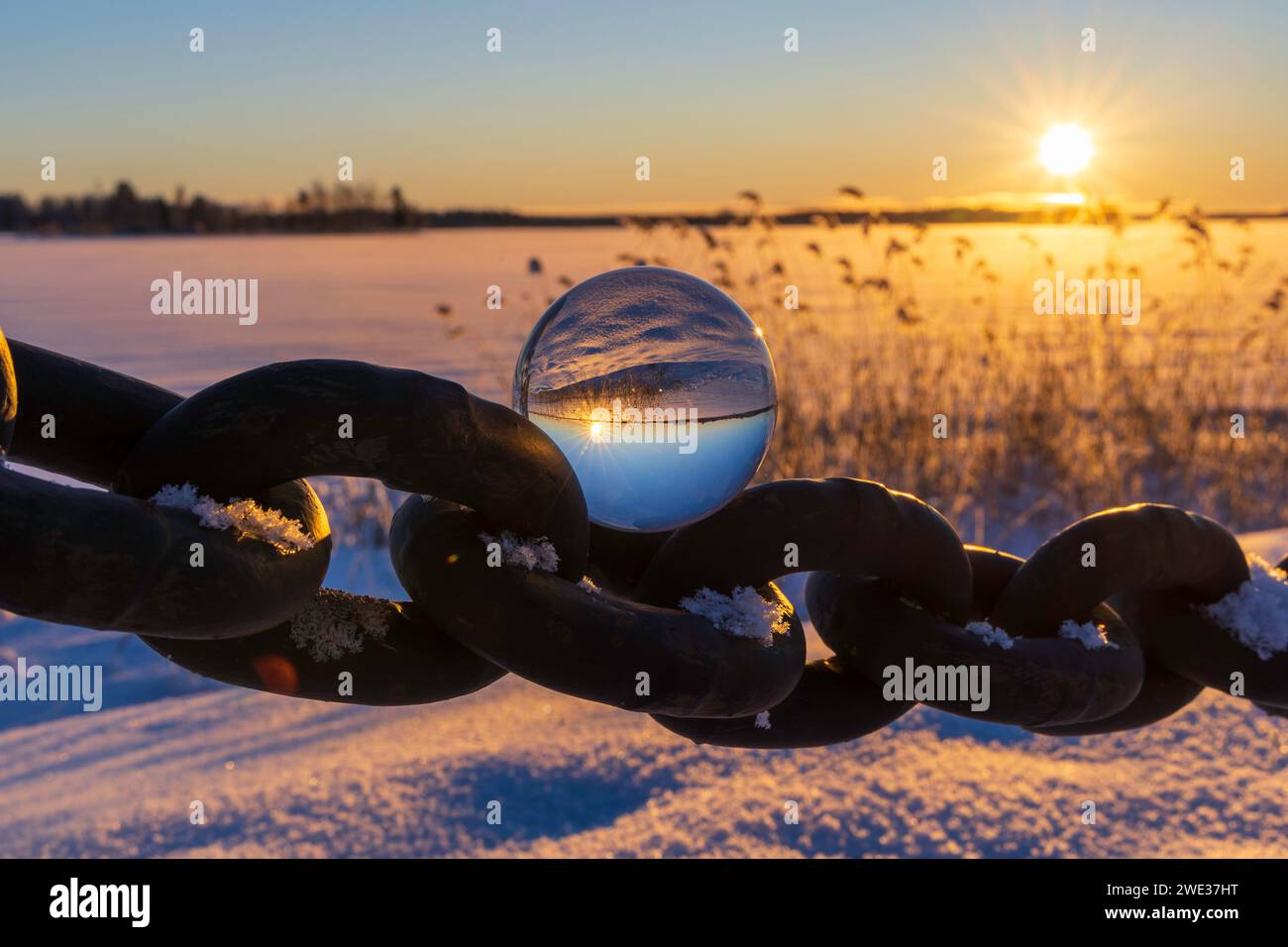 A glass ball on a chain link at sunset. Sandviken, Sweden Stock Photo