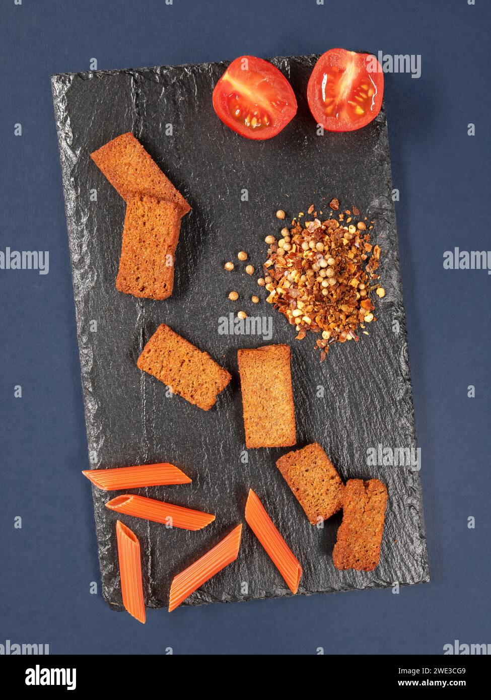 A visually appealing still life arrangement of fresh tomatoes, croutons, and an assortment of spices on a slate board. Ideal for culinary, cooking, or Stock Photo