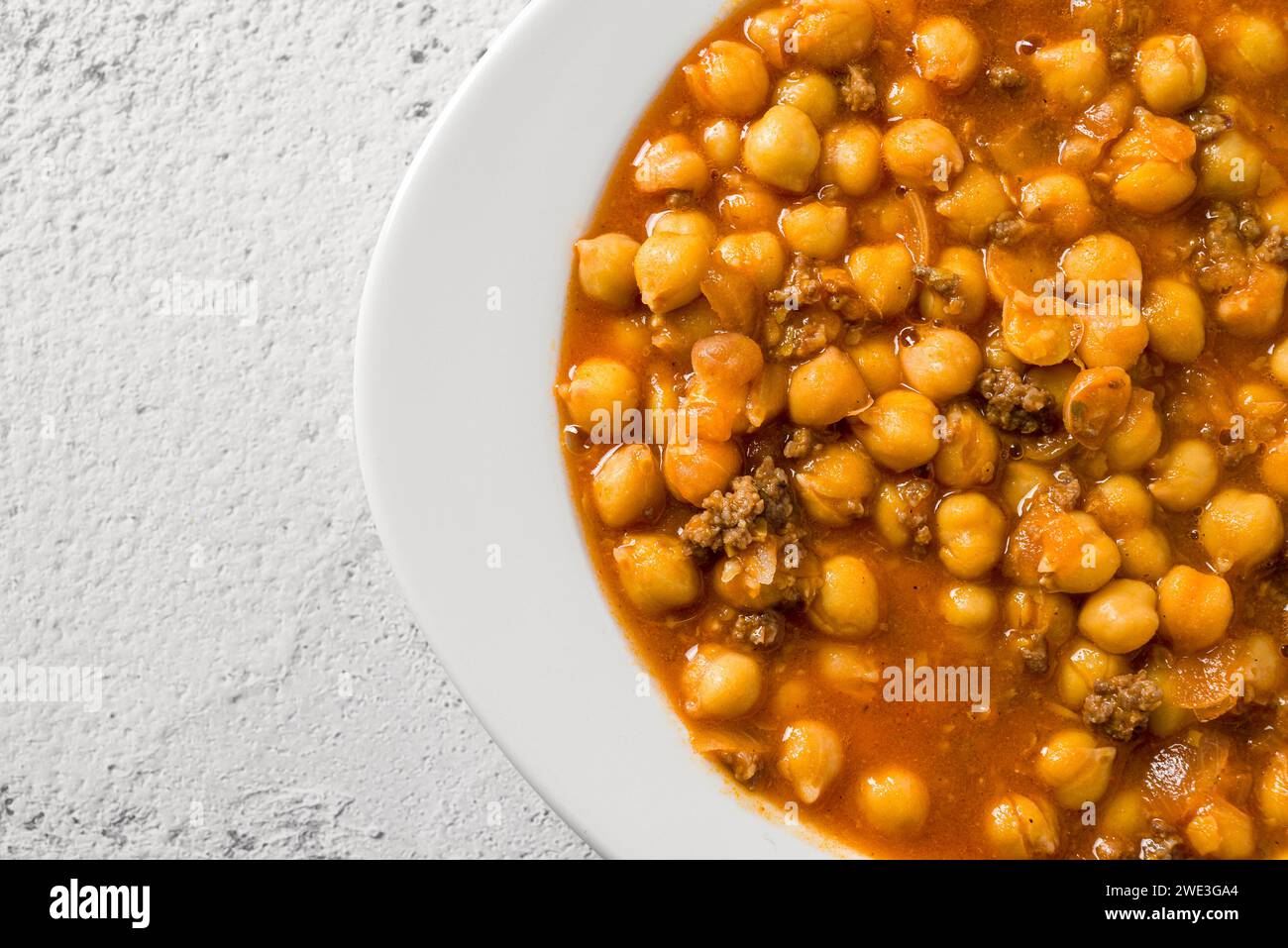 Chickpea stew with minced meat on a white porcelain plate on a stone table Stock Photo