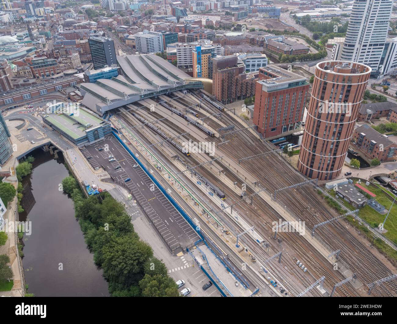 Aerial image of the roof, platforms, tracks, lines & trains at Leeds Station, with Candle House and Granary Wharf in Leeds city centre, Yorkshire, UK Stock Photo