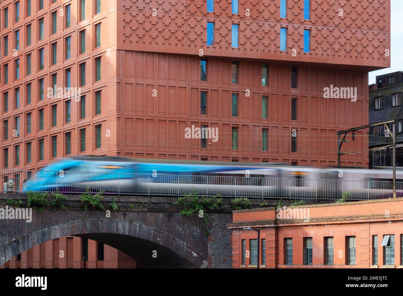 A high speed train running on an electrified line over a brick constructed Victorian viaduct next to the Maldron Hotel, Manchester, UK Stock Photo