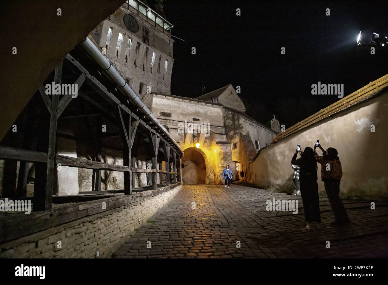 SIGHISOARA, ROMANIA - MAY 1, 2023: Unidentified tourists photograph the Clock Tower gate to the citadel of the medieval city at night. Stock Photo