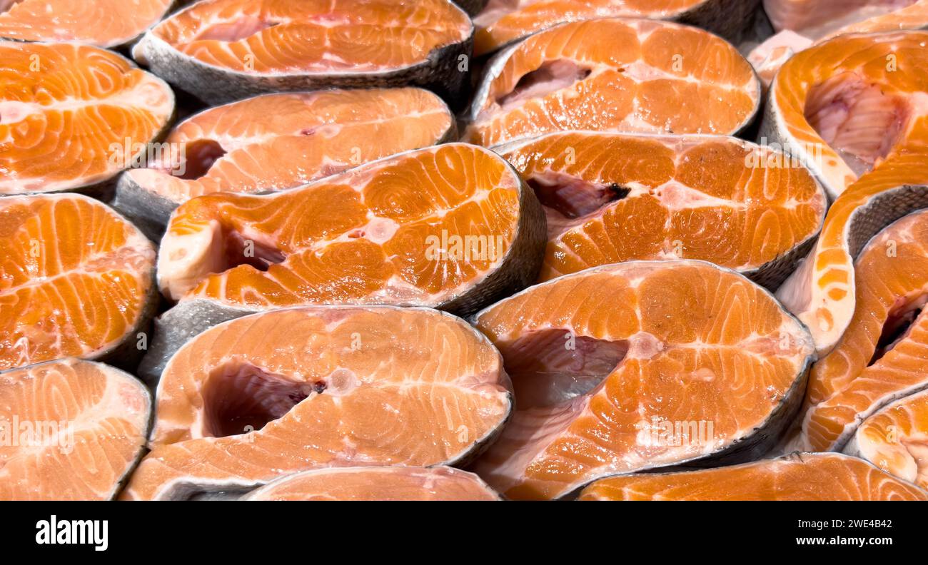 Fresh salmon steak texture background. Salmon red fish steak. Large Pile of trout steak. Big steaks of salmon lined up. Big pieces raw salmon. Stock Photo