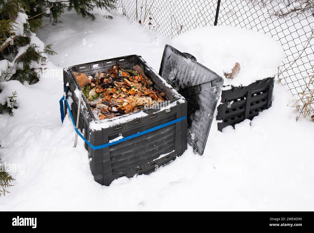 Showing open compost bin with bio waste inside, outdoors in the winter, snowy cold weather. Stock Photo
