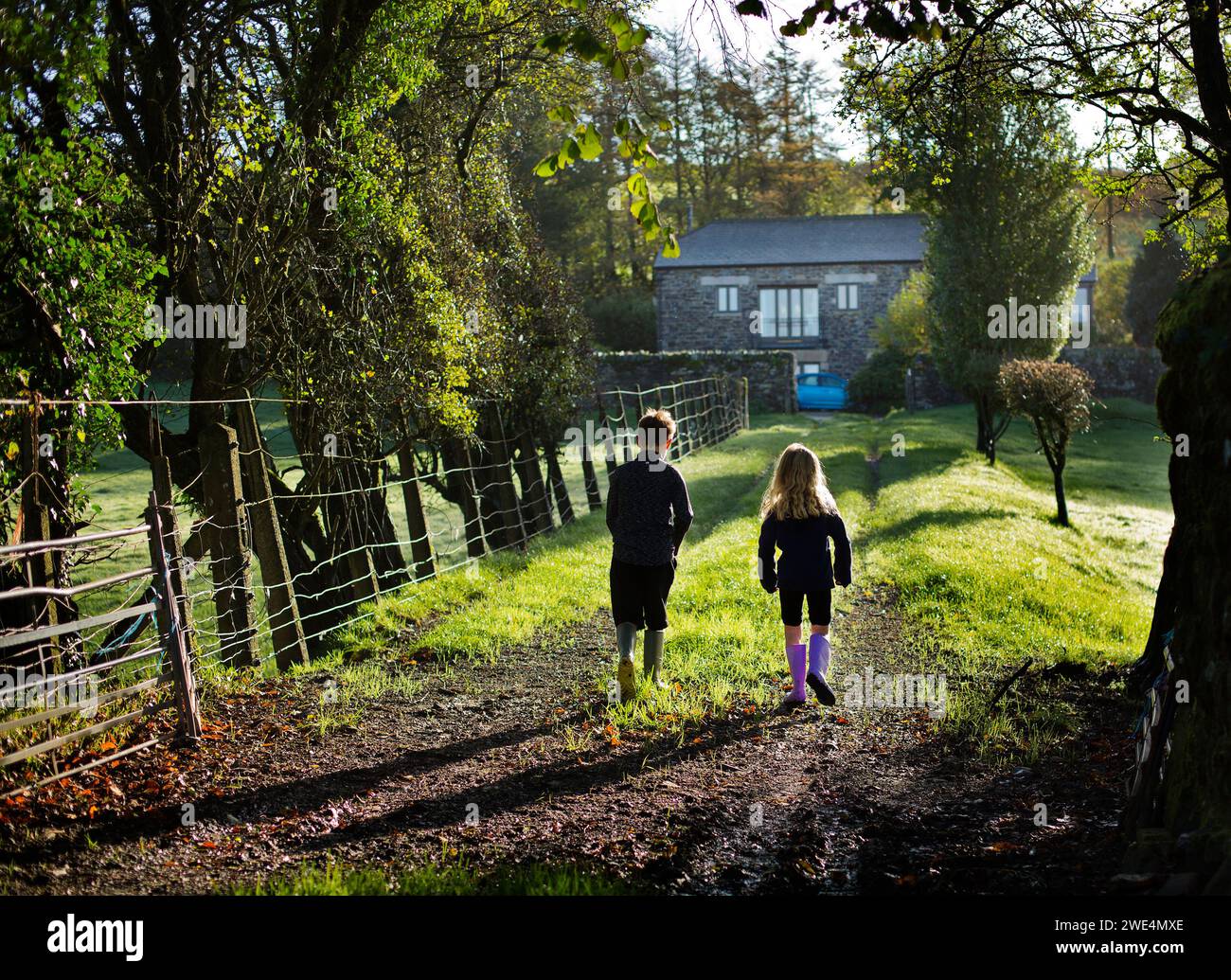 Two children walikng home up a track to a farmhouse Stock Photo